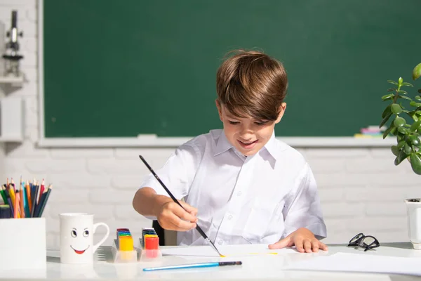 Chłopiec w szkole rysuje farbami. Kreatywność dzieci. malarstwo uczenia się dzieci. — Zdjęcie stockowe
