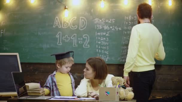 Family with little child boy reading book In playroom class. Happy cute clever boy. Child ready to answer with chalkboard on background. Ready for school. Schoolboy kids at elementary school. — Stok Video