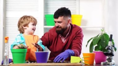 Family potting plant at home. Father ans son little child growing plant in pot. Happy loving family at home. Little cute boy helps his parents. Happy family planting sprout in a plant pot.