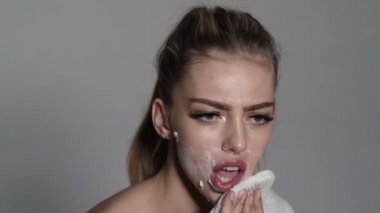 Trans gender concept. Woman shaving face. Angry young woman with foam on the face and a razor blade.