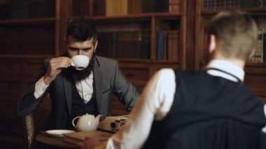 İş toplantısı. Klasik takım elbiseli iş adamı kitap okudu. Eski moda iş adamları. Kütüphanede arka planda kitapları olan işadamları.