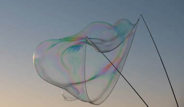 Gökkuşağı yansımalı sabun köpükleri. Mavi gökyüzünde kabarcıklar. Halat ve sopalarla kabarcık oluşturur..