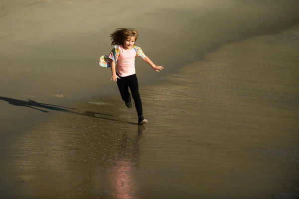 Niño feliz corriendo en la playa del mar. Chico gracioso corre a lo largo del borde del surf. Estilo de vida de niños activos. Un pequeño corredor haciendo ejercicio. Deportivo niño pequeño trotar y entrenar al aire libre. —  Fotos de Stock