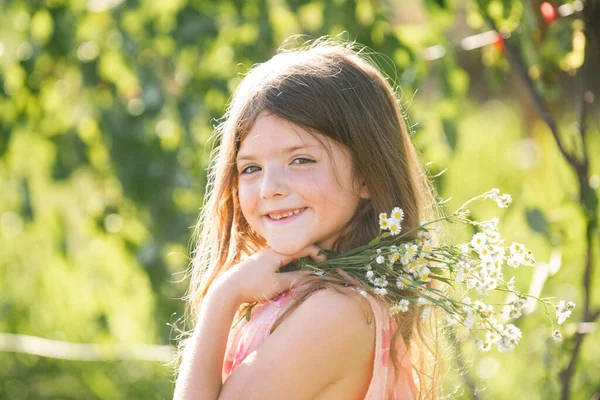 Πορτρέτο του όμορφου κοριτσιού στο ανθισμένο κήπο του καλοκαιριού. Ευτυχισμένο παιδί στο λιβάδι με λευκά λουλούδια. Ζεστό καλοκαιρινό βράδυ. Παιδιά και φύση. — Φωτογραφία Αρχείου