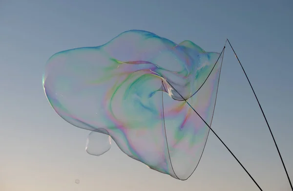 Grande bulle volant au-dessus du ciel bleu. D'énormes bulles de savon colorées volent sur fond de ciel nuageux. — Photo