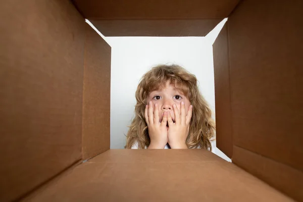 Engraçado garoto animado está abrindo presente e olhando dentro da caixa de papelão. Encomendas e entrega. — Fotografia de Stock