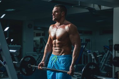 Halter kaldıran kaslı adam. Crossfit spor salonunda çalışan genç bir adam. Sporcu adam egzersiz yapıyor..