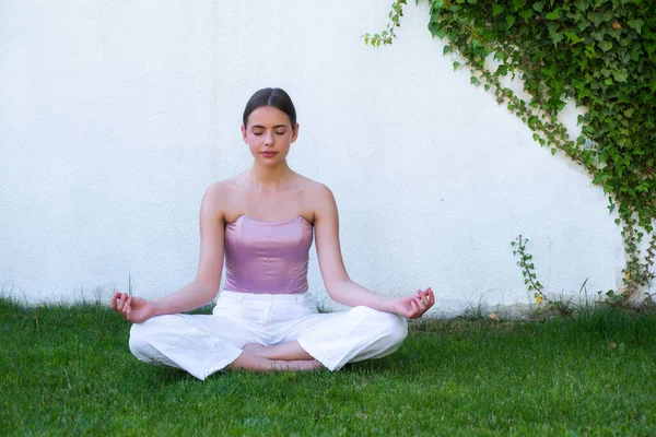 Meditazione yoga donna nel parco primaverile. Donna che si allunga. Giovane ragazza che pratica yoga, facendo esercizio fisico, lavorando su erba verde. — Foto Stock