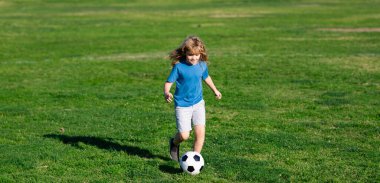 Futbolcu çocuk futbol oynuyor. Futbol topunu tekmeleyen tatlı çocuk. Dışarıdaki çimlerde top oynayan heyecanlı çocuk. Okul çocukları tarlada futbol oynuyor..