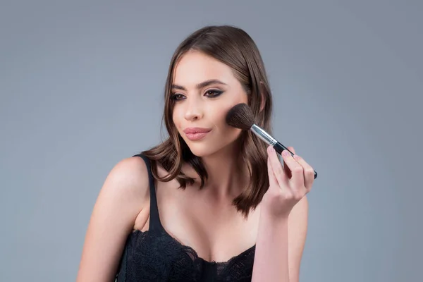 Portrét dívky s kosmetickým štětcem u obličeje. Žena drží štětec na líčení. Mladá krásná modelka s make-up ruměnec štětec a krásu obličeje použití make-up. Dívka drží červeň červeň, naneste prášek. — Stock fotografie