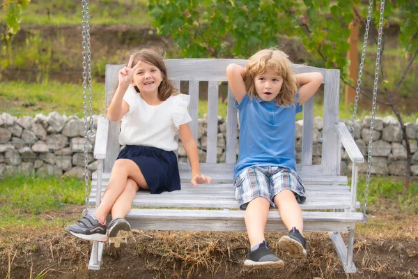 Petits enfants mignons jouant et se balançant à l'extérieur. Portrait de deux jeunes enfants heureux au parc d'été. — Photo