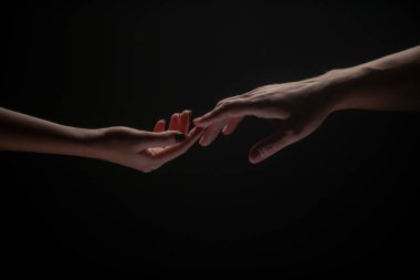 Parmaklarınla romantik dokunuş, aşkım. İki el birbirini gerer, siyah arka plan. Birbirine aşık çiftler, yaklaşın. Yardım eli, destek, arkadaşlık. Şefkat, şefkat dokunuşu.