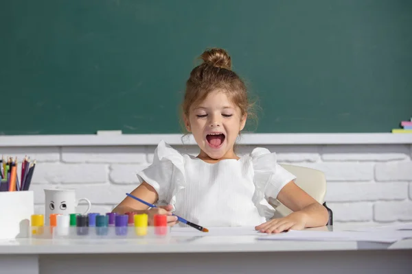 Nettes kleines Mädchen, das mit Farbe und Pinsel malt. Malschulstunde, Zeichenunterricht. — Stockfoto