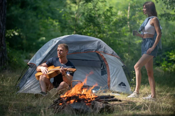 Romantic couple camping on nature background. Adventure for young friends on summer day. Carefree coupl near campfire bonfire, freedom concept. Lovely couple near fireplace Hiking couple in love.