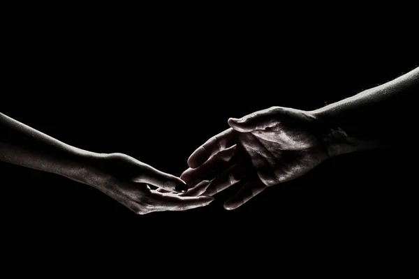 Two hands reaching toward. Helping hand outstretched for salvation on isolated black background. Close up of man and woman hand touch with fingers. Man and woman holding hands. — Fotografia de Stock