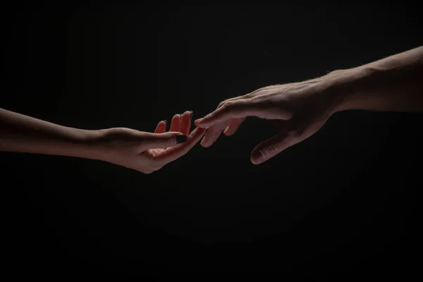 Romantický dotek prsty, lásko. Obě ruce se protáhnou, černé pozadí. Pár zamilovaných, držících holky, zblízka. Pomocná ruka, podpora, přátelství. Křehkost, dotek šlach. — Stock fotografie