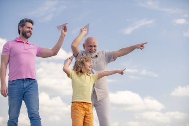 Üç farklı nesil, büyükbaba ve çocuk açık havada oyuncak uçakla oynuyorlar. Seyahat konsepti.