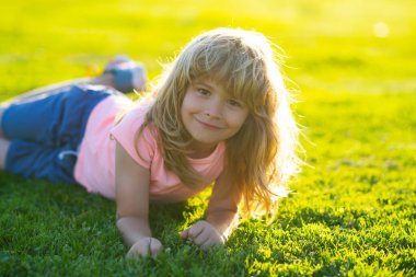 Yaz parkında küçük mutlu bir çocuğun portresi. Bahçedeki çayırda küçük şirin bir çocuk..