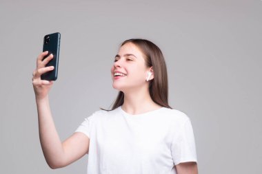 Kız selfie çekiyor. İzole edilmiş gri arka planı olan genç bir kadın..