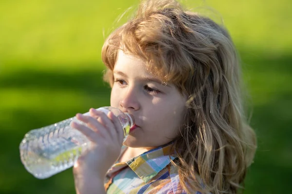 Close up ritratto di bambino ragazzo bere acqua da pet bottiglia all'aperto. — Foto Stock