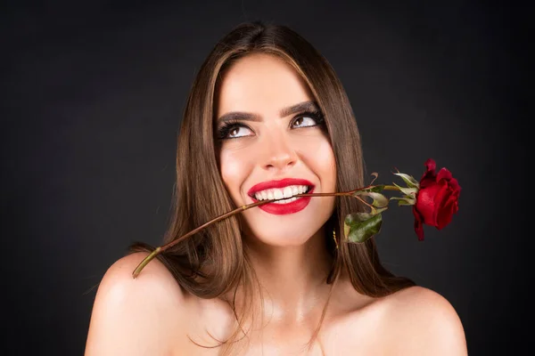 Kwiaty róży w ustach kobiet. Czerwone usta i róża. Piękna dziewczyna z zmysłowymi ustami. Seksowna kobieta z czerwoną różą w zębach na czarnym tle. Koncepcja Dnia Kobiet. Wszystkiego najlepszego. — Zdjęcie stockowe