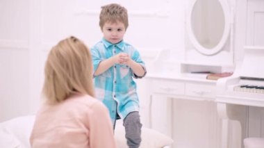 Anne ve çocuk yatak odasında konuşuyor. Mutlu anne ve küçük oğlu evde yatakta oynuyorlar. Günaydın..