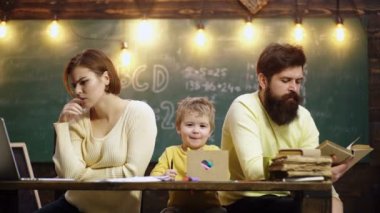 Çocuklar evde öğrenir ve öğrenirler. Oyun odasında kitap okuyan küçük çocuklu bir aile. Mutlu, zeki çocuk. Çocuk arka planda yazı tahtasıyla cevap vermeye hazır. Okula hazırım..