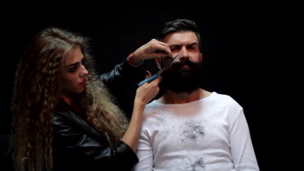 Frisör eller frisör. Sexig kvinna frisör skär skägg med sax. Kvinnlig frisör. Man med långt skägg, mustasch och stilrent hår. — Stockvideo