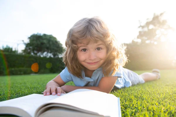 Okos fiú olvasni könyvet zöld fű. — Stock Fotó