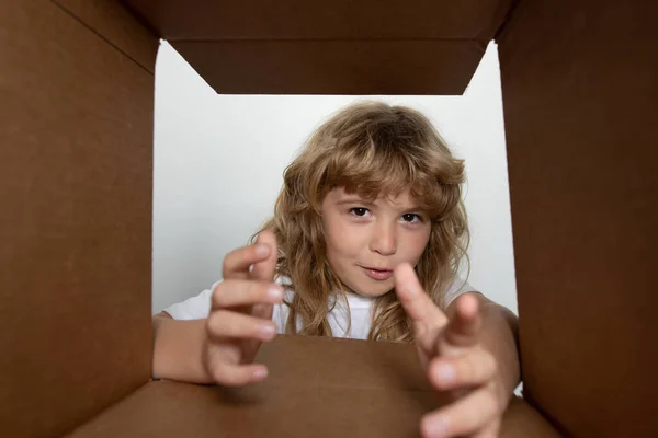 L'enfant surpris âge 8 ans déballer, ouvrir la boîte en carton et regarder à l'intérieur. Le paquet, la livraison, la surprise, le concept de cadeau pour enfants. Parcelles, service de livraison. — Photo
