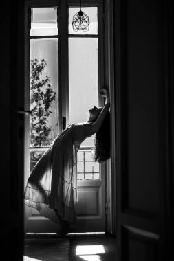 O mutlu dans eder. Balkonun yanında duran genç bir kadın. Yalnız bir kadın. Kendine güveni tam seksi bir kız. Tutku ve cazibe. Kız gece elbisesi giymiş..