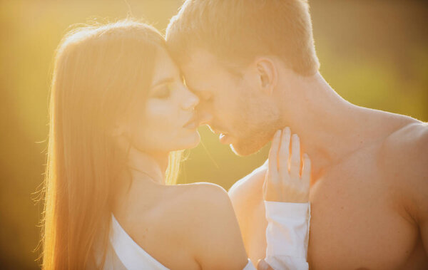 Sensual kiss. Man kissed tender woman at sunset. Sensual portrait of young couple in love. Loving couple embracing and kissing.