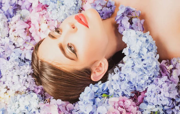 La belleza natural. Mujer acostada sobre flores. Unidad con la naturaleza. Blossom. Maquillaje cosmético y cuidado de la piel. Chica con flores de hortensias. — Foto de Stock