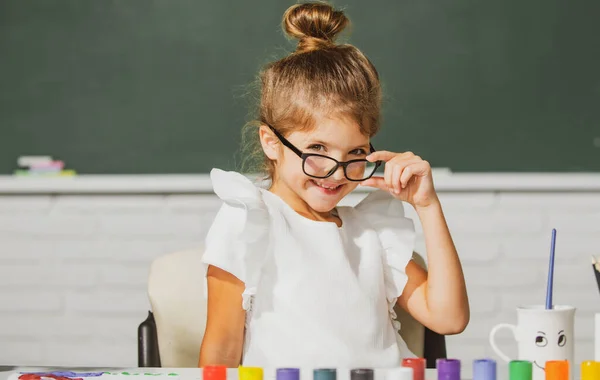 Bonito cara menina da escola com óculos. Meninas desenhando um colorido imagens com lápis lápis lápis na sala de aula da escola. Pintura crianças. — Fotografia de Stock