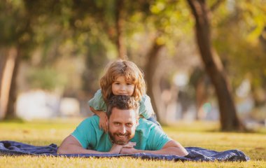 Baba ve oğul çimenlerde uzanıp parkta doğada dinleniyorlar. Çocukluk ve ebeveynlik kavramı.