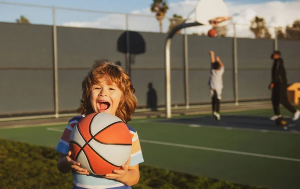 Basket míč vzrušený dětský hráč se směje a baví. Basketbalová škola pro děti. — Stock fotografie