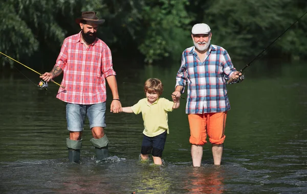 Риболовля для форелі. Старий і молодий. Портрет щасливого маленького сина, батька і дідуся - три покоління чоловіків, що рибалять на річці . — стокове фото