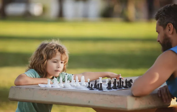 Ojciec i syn grający w szachy spędzają razem czas na świeżym powietrzu. Gry i zajęcia dla dzieci. — Zdjęcie stockowe