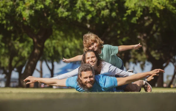 Doğada eğlenen çocuklu genç bir aile. Sinek konsepti, küçük çocuk uçuşu taklit ederken kazma gibi oturuyor. Seyahat hayali.