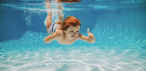 Undervattensbarn simmar i vatten pool. Sommar aktivitet och friska barn livsstil. Sommarsemester med barn i en tropisk semesterort. Grabben med tummen upp under vattnet. — Stockfoto