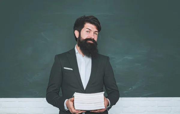 Retrato de estudiante universitario masculino en el interior. Concepto de educación de estudiantes y tutoría. Concepto de aprendizaje y educación. Examen en la universidad. Profesor barbudo en clase de la escuela en los escritorios en el aula. —  Fotos de Stock