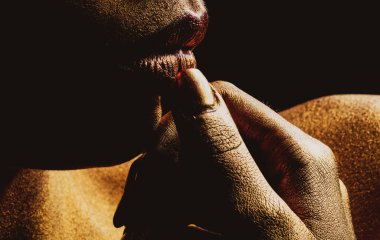 Kadın yüzünde altın rengi boya. Altın dudaklar yakın çekim. Altın metal dudak. Güzel makyaj. Güzel kadın ağzında altın dudak parlatıcısı, yakın plan..