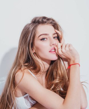 Yatakta battaniyeli ve kameraya bakan neşeli genç bir kadın. Şehvetli kız yatakta uyuduktan sonra kendini zinde hissediyor. Gülen kadın yastık ve battaniyeyi kucaklarken eğleniyor..