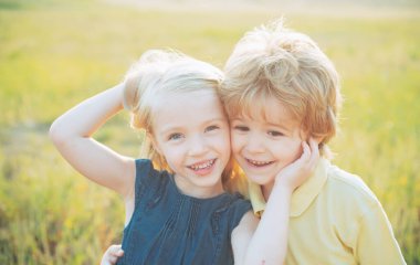 Çocuklar doğaya karşı sahada eğleniyorlar. Romantik ve aşk dolu. Çocuk bahar tarlasında eğleniyor. Mutlu şirin çocukların yaz portresi. Küçük şirin çocuklar kırsalda eğleniyor..