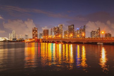 Miami, Florida şehir merkezi Biscayne Körfezi 'nde. Günbatımında şehir gökdelenleri ile Panorama ve yansıma ile deniz üzerinde köprü.
