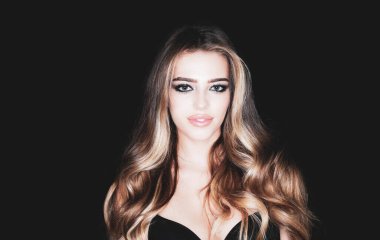 Kozmetik güzellik ve kaplıca. Güzellik ve güzellik merkezi. Moda butiği reklamı. Yüksek moda. Sarışın, kıvırcık saçlı, siyah arka planda gülümseyen bir kadın..