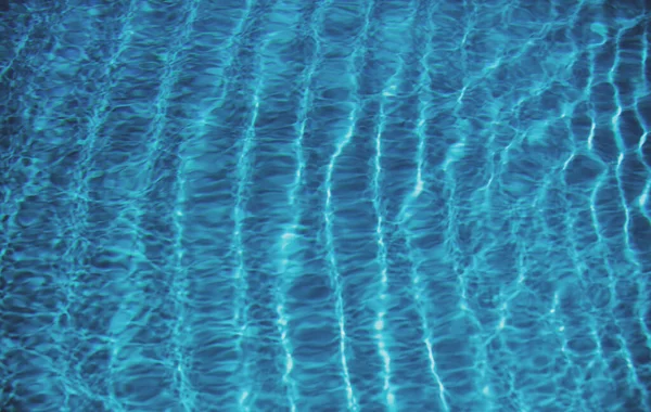 Fondo blu dell'acqua della piscina. Trasparente trasparente sfocato superficie dell'acqua calma texture. Onde d'acqua alla luce del sole con spazio copia. — Foto Stock