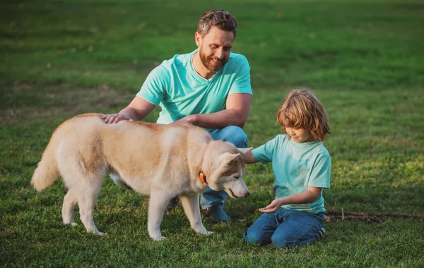 Infância e paternidade conceito crianças. Feliz pai e filho brincando com cão de estimação ao ar livre. Criança com seu amigo de estimação. — Fotografia de Stock