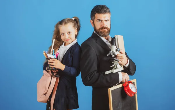 아버지 와동 생딸은 학교에 갈 준비가 되어 있다. 파란 배경에 고립된, 학교 용품을 가지고 있는 아버지와 어린 소녀의 모습. — 스톡 사진