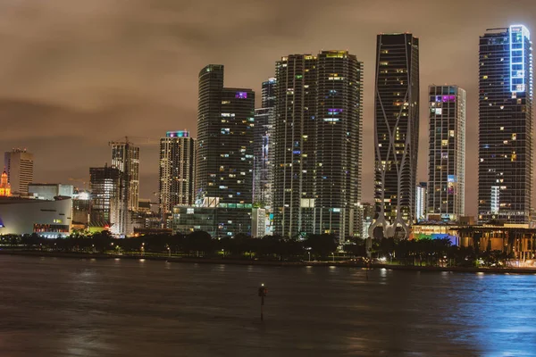 Miami Florida napnyugtakor, kivilágított épületek és a Macarthur Causeway híd. Miami éjszaka a belvárosban, város Florida. — Stock Fotó